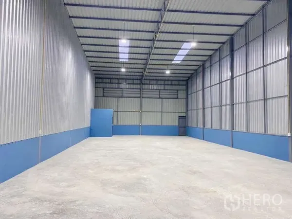 Warehouse for rent in Pak Kret, Nonthaburi - High-clearance warehouse interior with metal walls, skylights, and bright LED lighting.