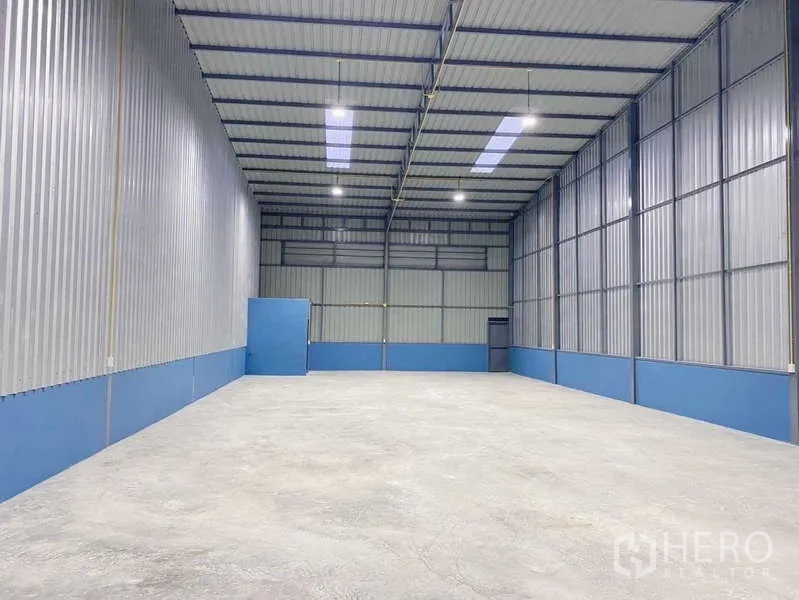 Warehouse for rent in Pak Kret, Nonthaburi - High-clearance warehouse interior with metal walls, skylights, and bright LED lighting.