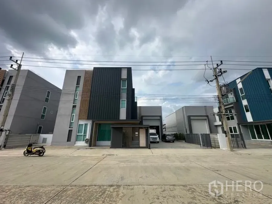 货栈 出售在Pathum Thani - 三层现代办公楼外观，连体仓库与门前停车位，位于Lam Luk Ka宽阔街道。