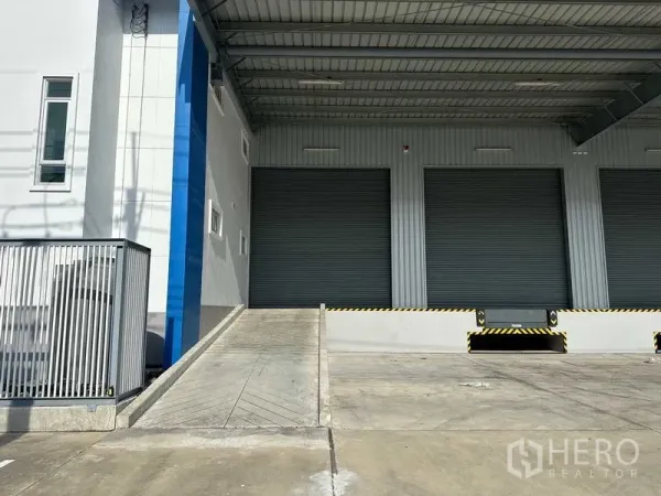 工厂 出租在Bang Sao Thong, Samut Prakan - 通往装卸月台的坡道，带雨棚与关闭的卷闸门，便于卡车进出