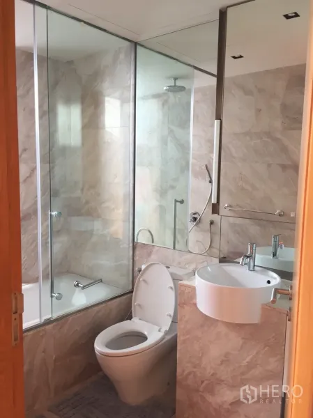 Condominium for rent or sale in Sathon, Bangkok - Marble bathroom with glass-enclosed bathtub, rain shower and round basin.