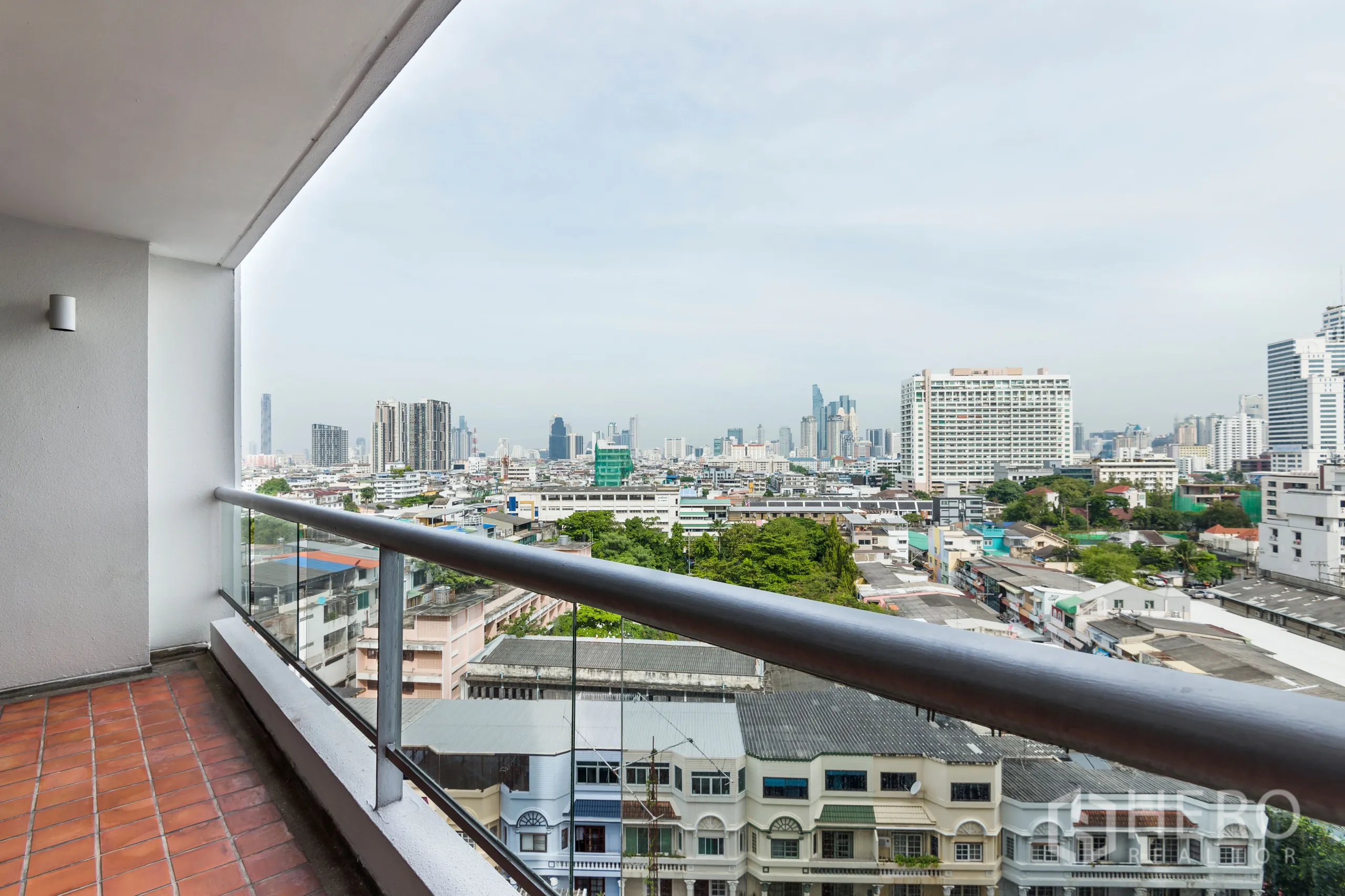 Condominium for rent in Yan Nawa, Bangkok - Covered balcony with glass railing and terracotta tiles overlooking the city skyline.