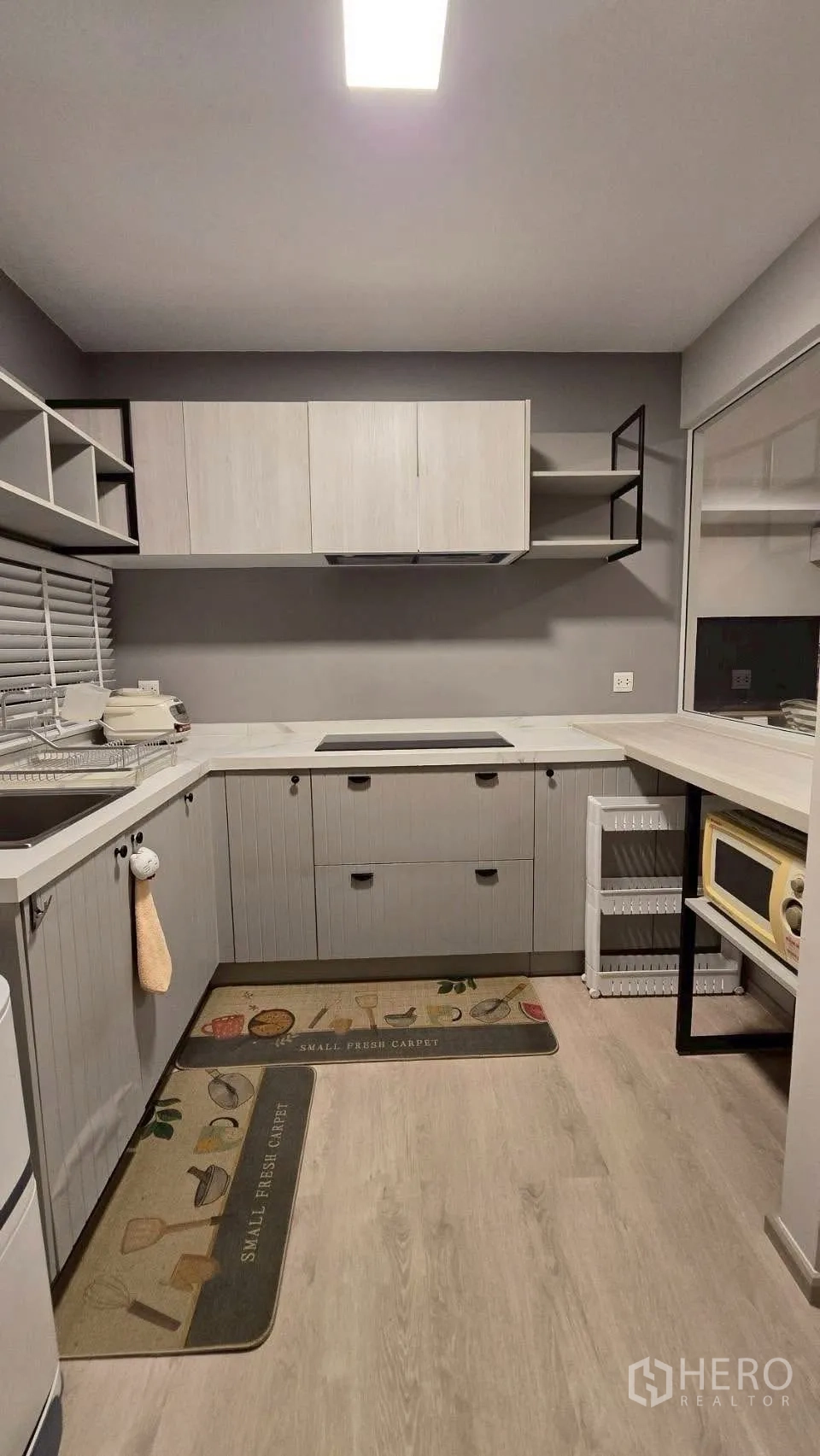 Semi-detached House for rent in Prawet, Bangkok - Modern L-shaped kitchen with cabinets, solid countertops and an induction hob.