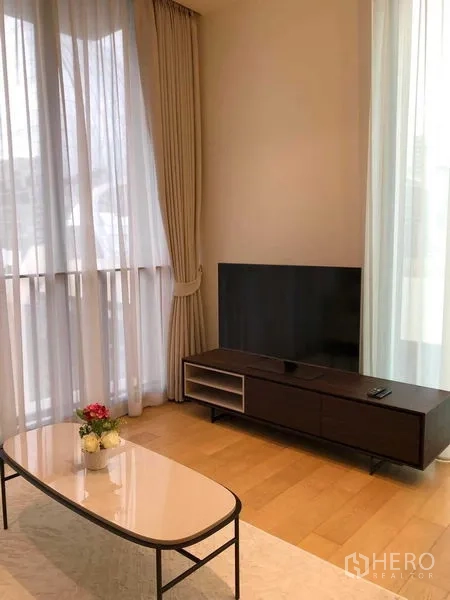 Condominium for rent - TV console and coffee table in a light-filled living room with sheer curtains.