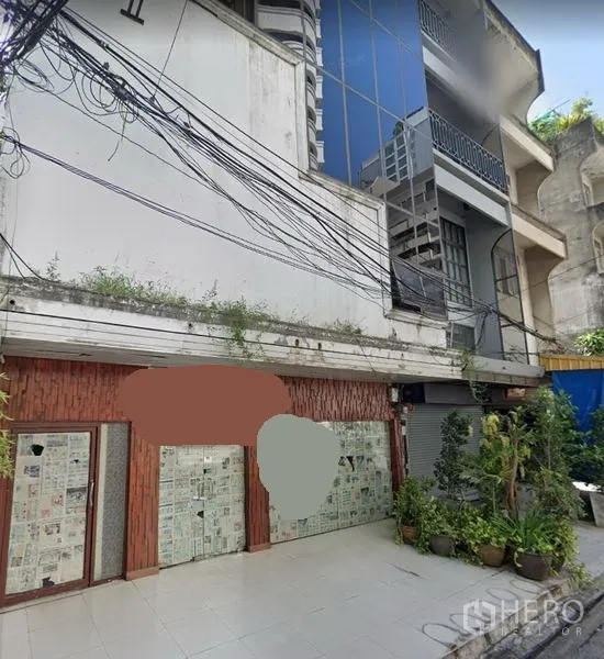 อาคารพาณิชย์ ให้เช่าหรือขายในKhlong Toei, Bangkok - อาคารพาณิชย์ติดถนน ด้านหน้าปูพื้นกระเบื้อง มีหน้าร้านกระจกปิดด้วยกระดาษ กระถางต้นไม้ และสายไฟเหนือศีรษะ ในบรรยากาศเมืองกรุงเทพฯ