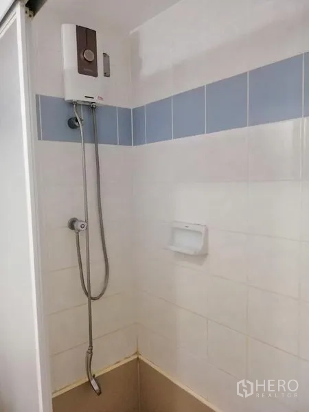 Condominium for rent in Watthana, Bangkok - Shower area with instant water heater and white tiled walls.