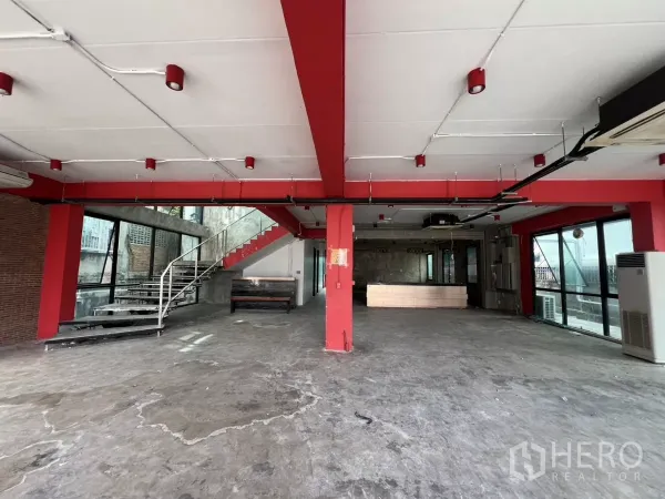 独立商业地产 出租在Din Daeng, Bangkok - 宽敞室内，红色立柱、楼梯与接待台，工业风格。