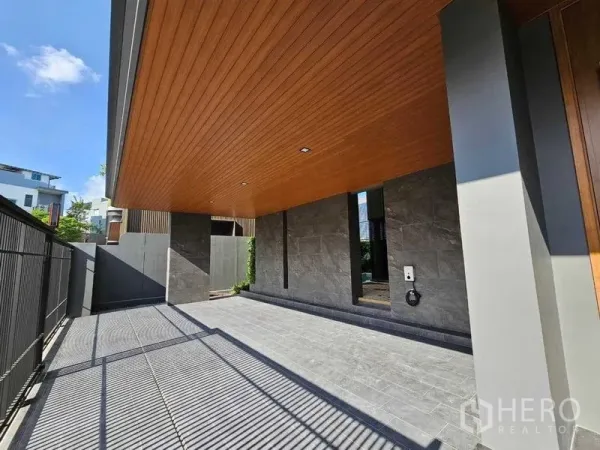 บ้าน ให้เช่าในWang Thonglang, Bangkok - พื้นที่จอดรถมีหลังคา ฝ้าไม้ และพื้นหิน ข้างรั้วเหล็ก