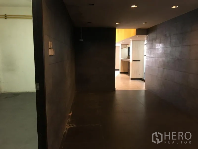 零售空间 出租在Khlong Toei, Bangkok - 带嵌灯的深色走廊，通往主要营业区。