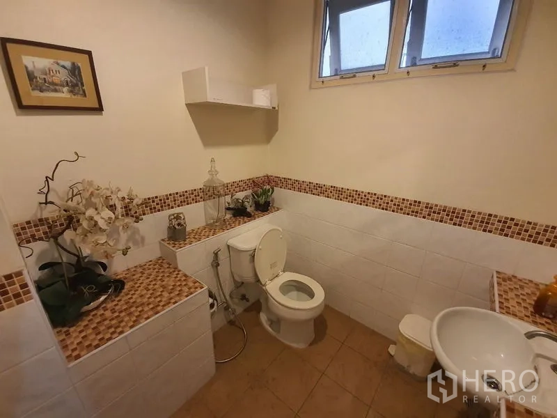 Townhouse for rent in Phaya Thai, Bangkok - Guest bathroom with mosaic trim, toilet, sink and decorative accents.