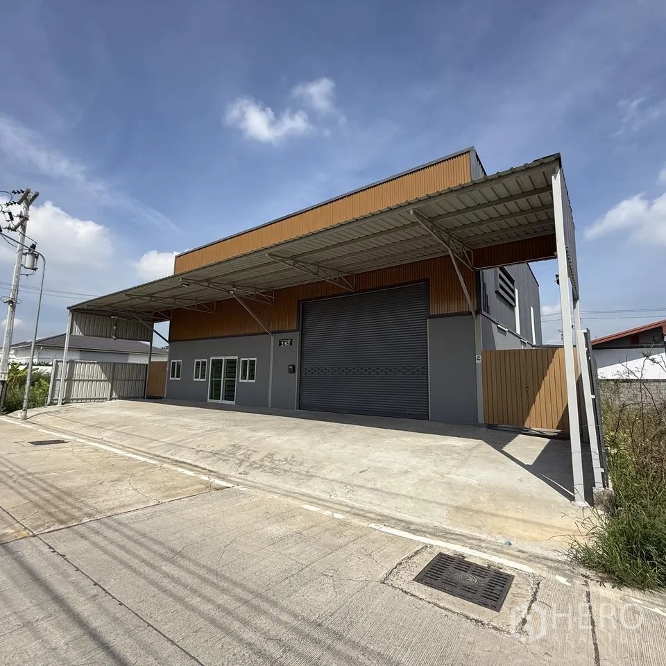 仓库 for rent or sale in Khlong Luang, Pathum Thani - 正立面带有遮雨装卸区、宽幅卷闸门与车道。