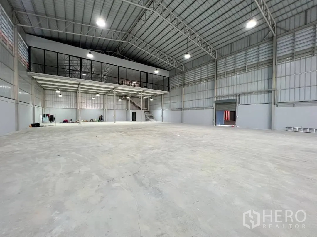 货栈 出租在Sai Mai, Bangkok - 高挑顶仓库空间，带整面玻璃夹层办公室与宽大卷帘门。