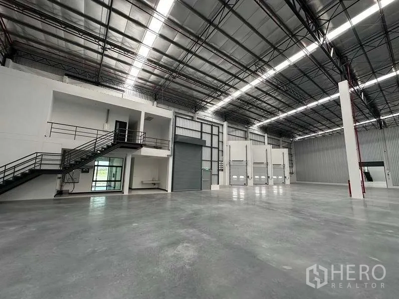 工厂 出租在Phan Thong, Chon Buri - 仓库一侧可见卷闸门、装卸月台与办公区。