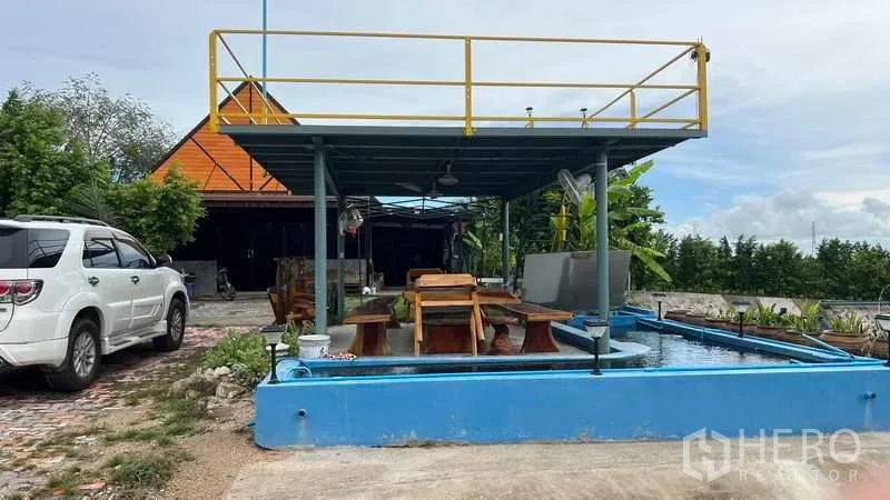 工厂 出售在Nikhom Phatthana, Rayong - 户外员工餐休区，设有高架平台与座椅，旁有水池。