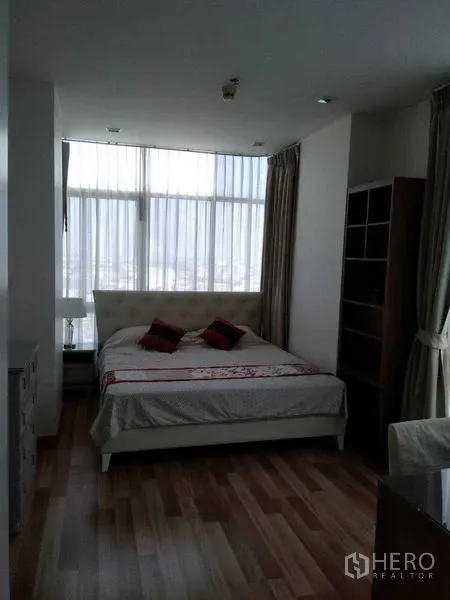 Condominium for rent in Watthana, Bangkok - Bright master bedroom with large windows, sheer curtains, and wood flooring.