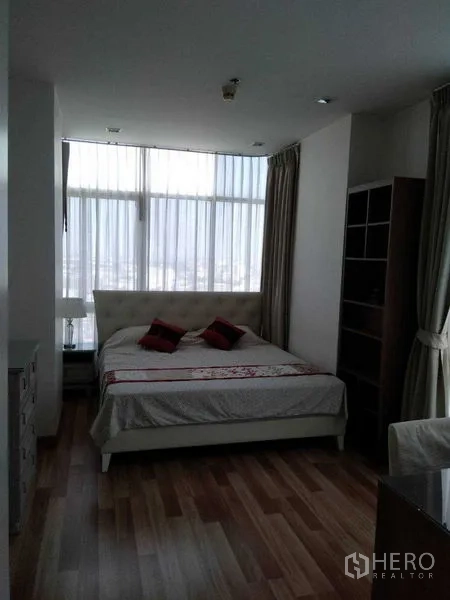Condominium for rent in Watthana, Bangkok - Bright master bedroom with large windows, sheer curtains, and wood flooring.