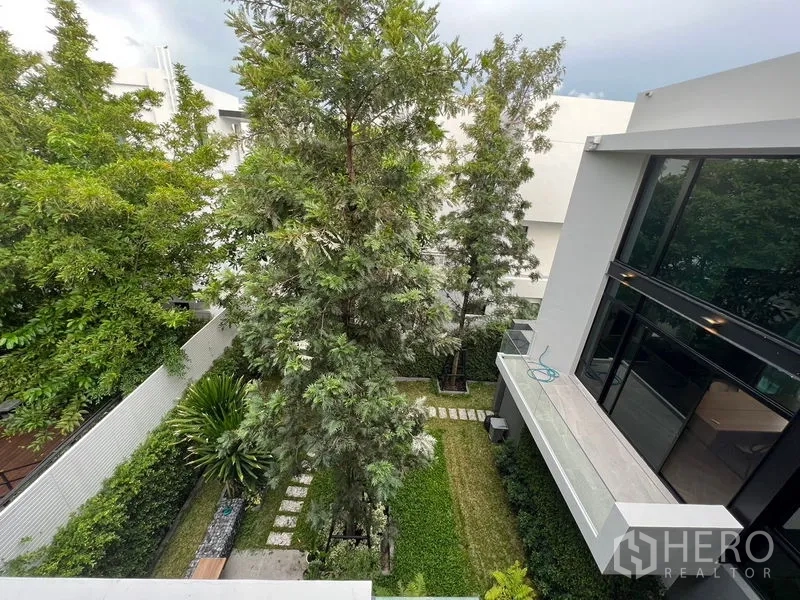 Detached House for sale in Saphan Sung, Bangkok - Aerial view of a landscaped courtyard with mature trees, lawn and stepping stones.