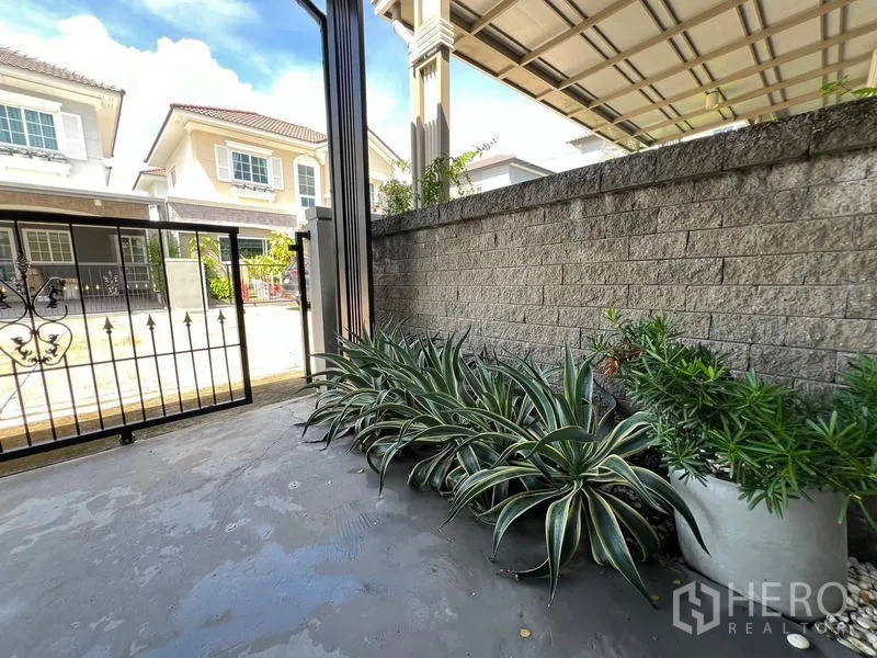 Detached House for rent or sale - Front gate area with potted plants and a textured brick wall.