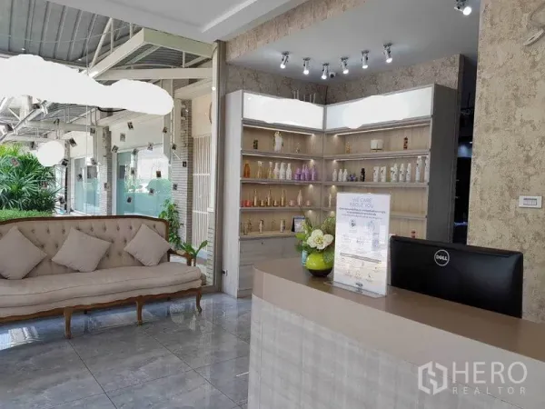 พื้นที่ขายปลีก ให้เช่าในWatthana, Bangkok - เคาน์เตอร์ต้อนรับและโซฟารับแขกหันเข้าหาชั้นโชว์สินค้ามีไฟ พร้อมทางเดินเปิดโล่งและต้นไม้เขียว