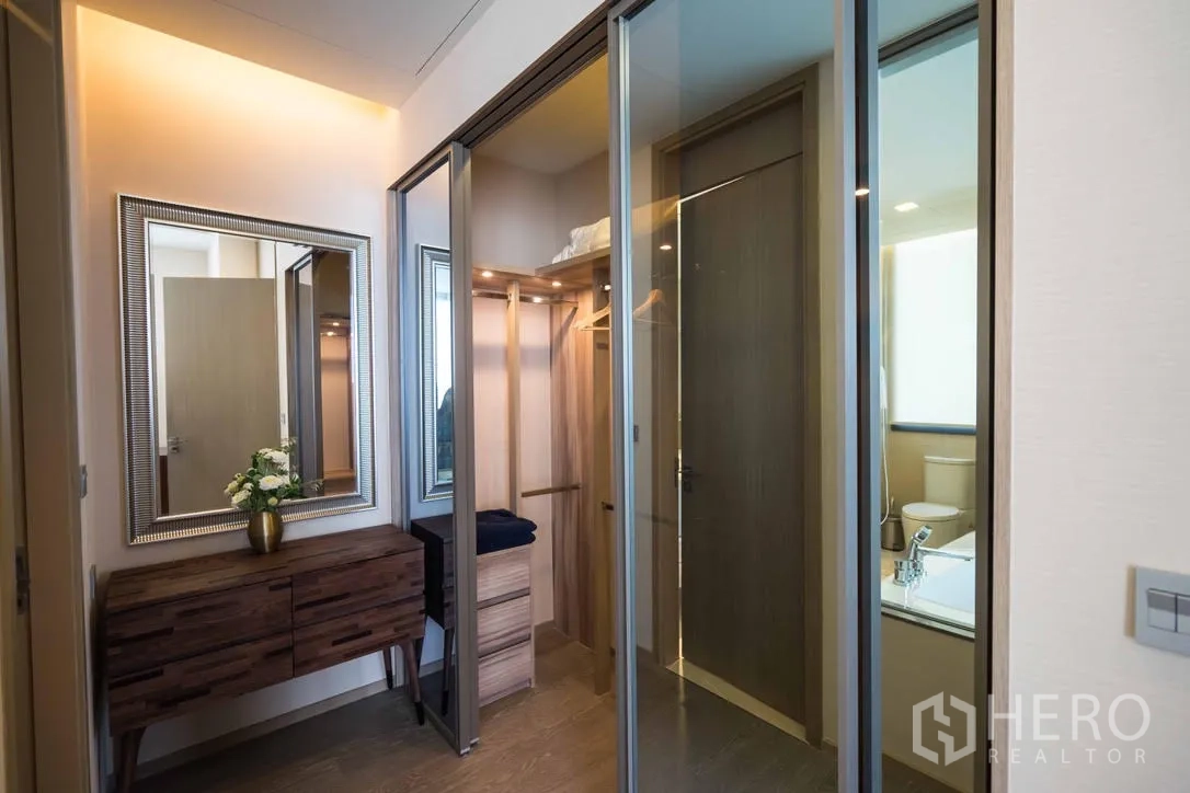Condominium for rent in Watthana, Bangkok - Walk-in closet and dressing area with mirrored sliding doors and wood cabinetry.