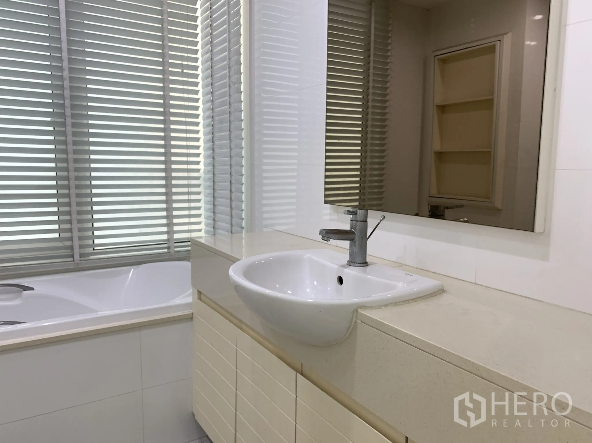 公寓 出租在Khlong Toei, Bangkok - 浴室配长台面、台盆和靠百叶窗的浴缸。