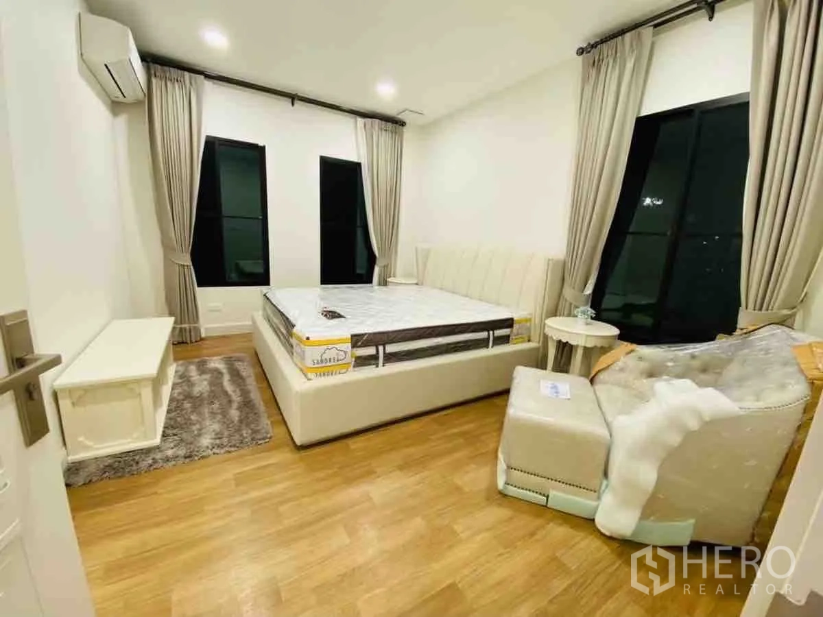 Detached House for rent or sale in Saphan Sung, Bangkok - Secondary bedroom with bed and armchair, warm lighting and curtains