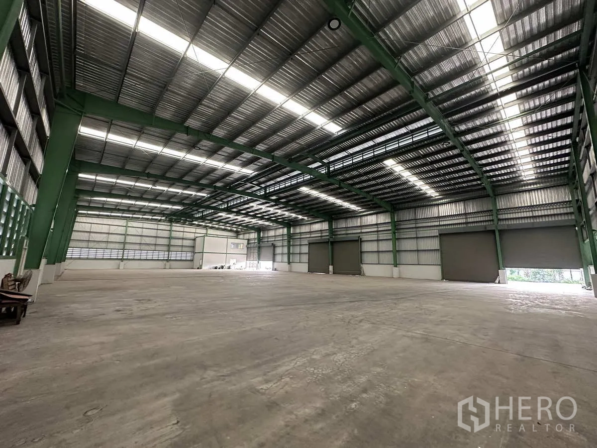 โรงงาน ให้เช่าในMueang Samut Prakan, Samut Prakan - โซนผลิตพร้อมประตูม้วนขนาดใหญ่สามบาน โครงสร้างเหล็ก และแสงธรรมชาติ