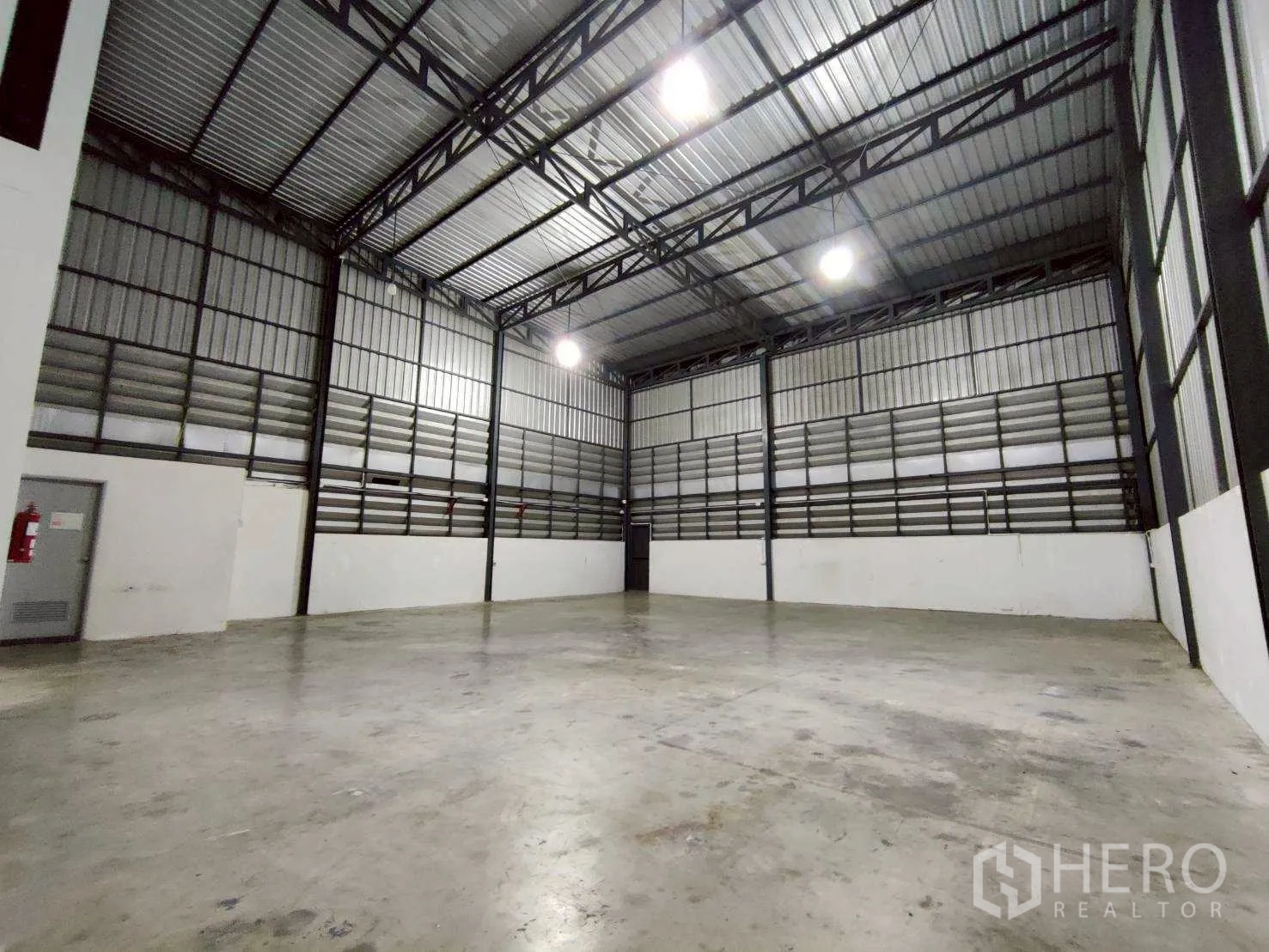 Warehouse for rent in Lam Luk Ka, Pathum Thani - Empty warehouse floor with metal cladding walls and overhead lighting.