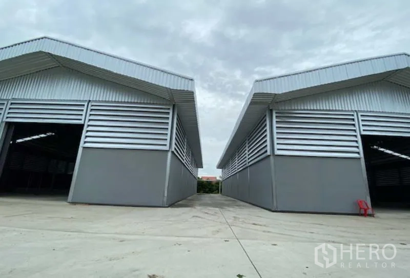 Factory for rent in Pathum Thani - Two parallel warehouse bays with large roller doors and a spacious truck driveway at an industrial site in Pathum Thani.