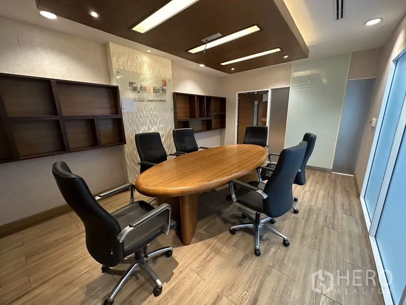 Office Space for rent or sale - Boardroom with oval wooden table, leather chairs, and feature ceiling lighting.