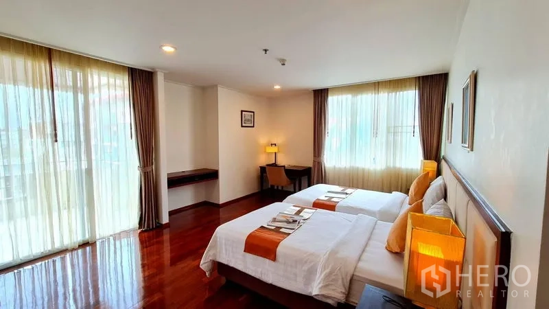 อพาร์ทเมนท์ ให้เช่าในKhlong Toei, Bangkok - อีกมุมของห้องนอนเตียงเดี่ยวคู่ แสดงหน้าต่าง โคมไฟข้างเตียง และโต๊ะทำงาน