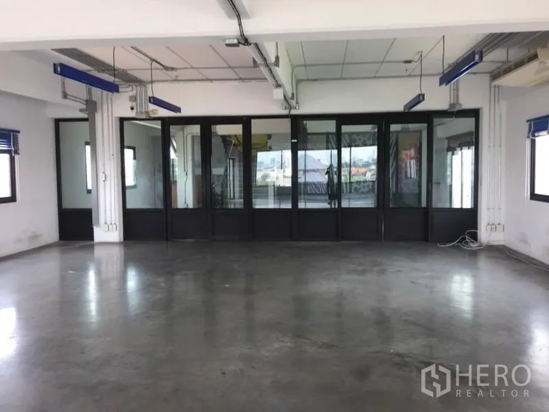 Home Office for rent or sale in Wang Thonglang, Bangkok - Spacious office area facing black-framed glass meeting rooms with multiple windows.