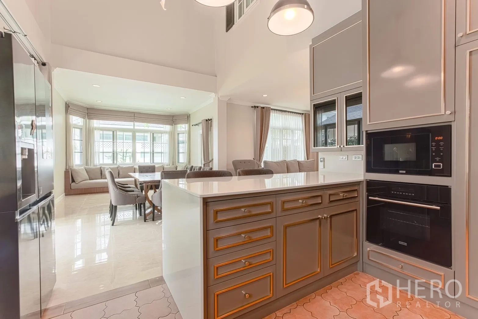 Detached House for rent in Bang Na, Bangkok - Kitchen island facing dining area with bay window seating and floor-to-ceiling windows.