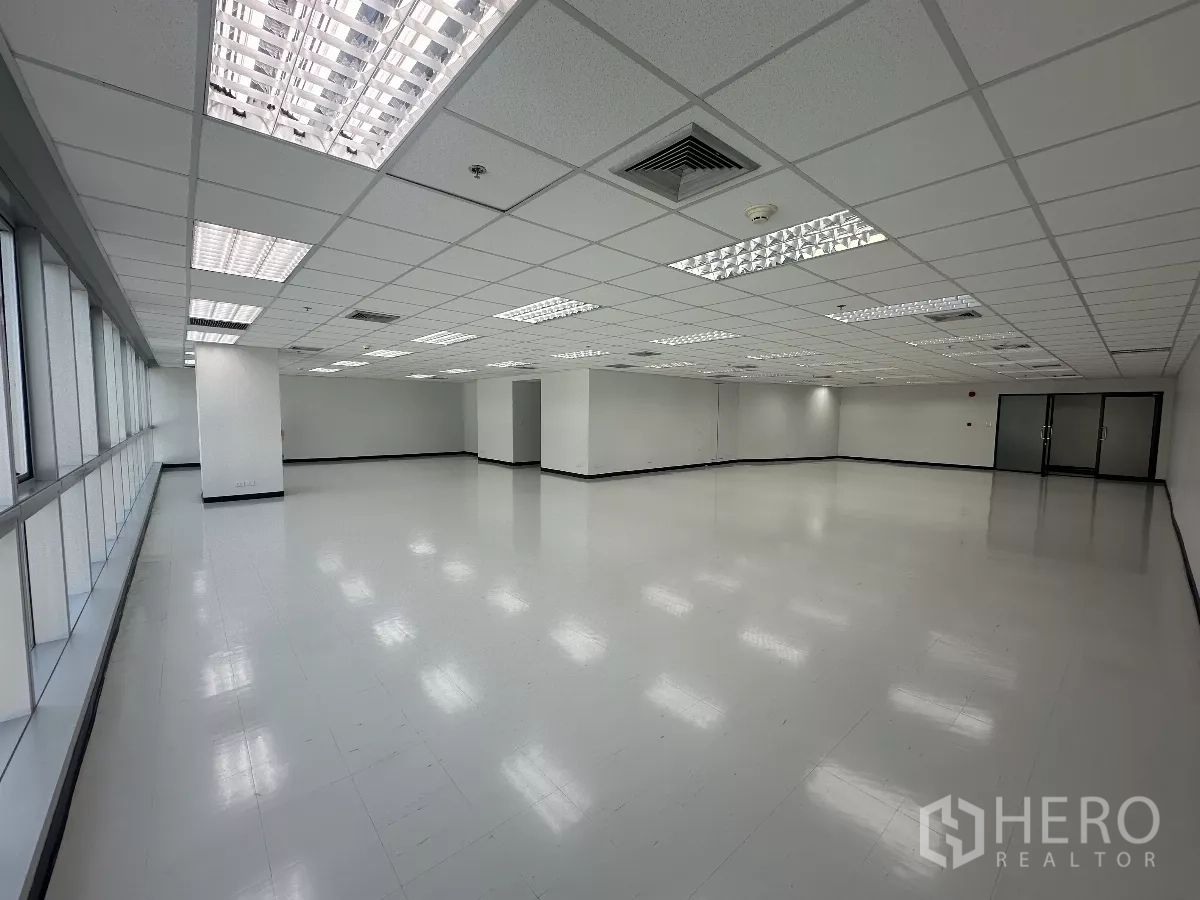 Office Space for rent in Watthana, Bangkok - Spacious open office interior with a long window wall, suspended ceiling lighting, and double glass entry doors.