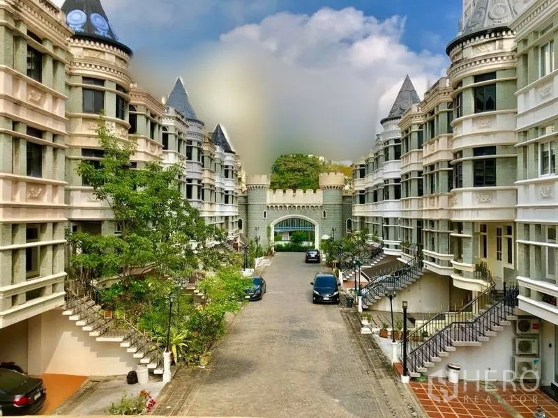 Home Office for rent in Watthana, Bangkok - Gated community view with castle-style townhouses and a central driveway.