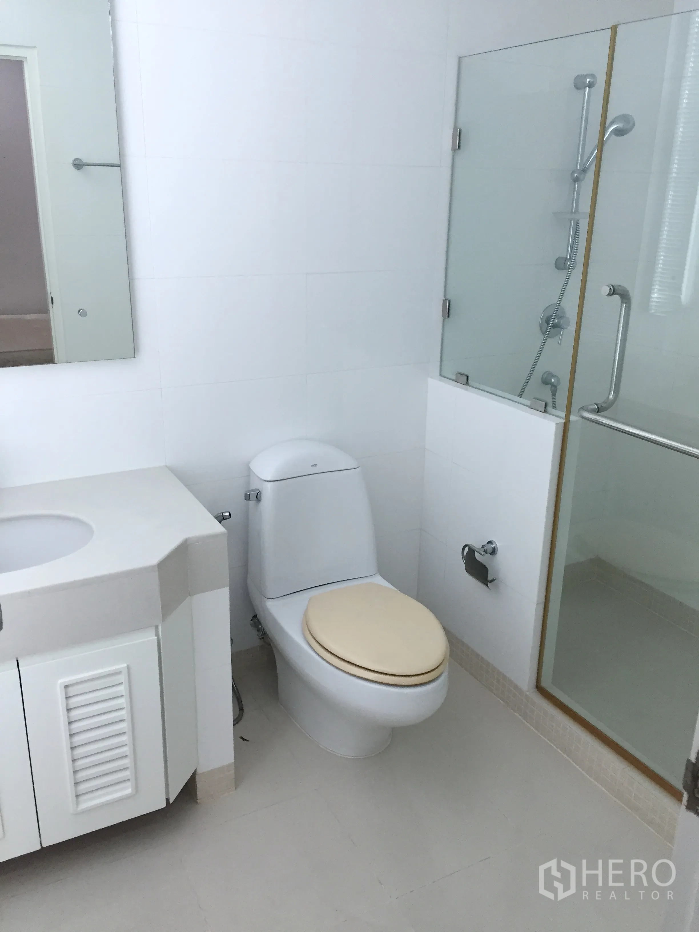 公寓 出租在Khlong Toei, Bangkok - 洁白浴室，坐便器、洗手柜与玻璃淋浴房。