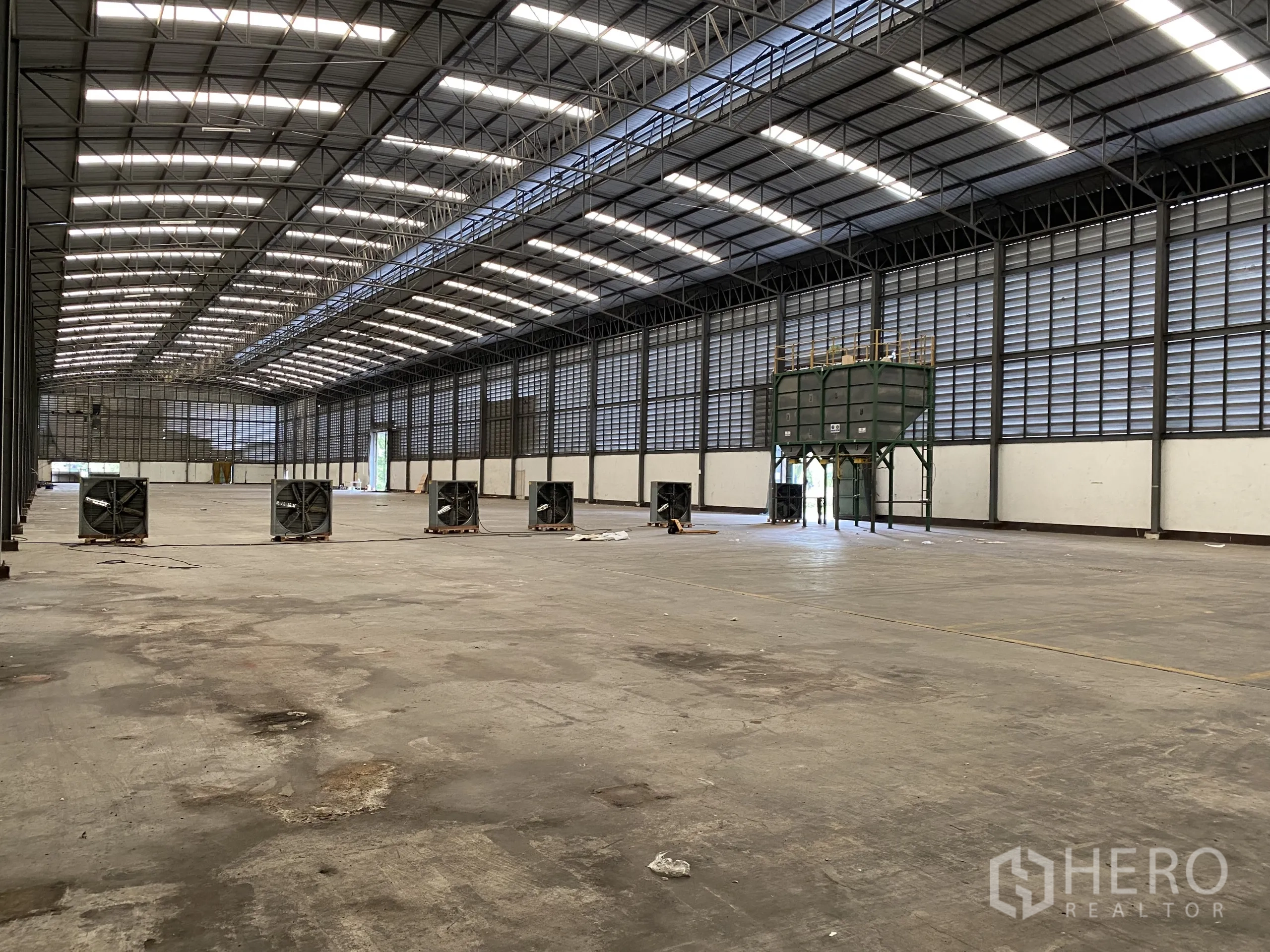 Factory for rent in Ban Phaeo, Samut Sakhon - Empty production hall showing multiple large floor fans, louvered walls and wide clear span.