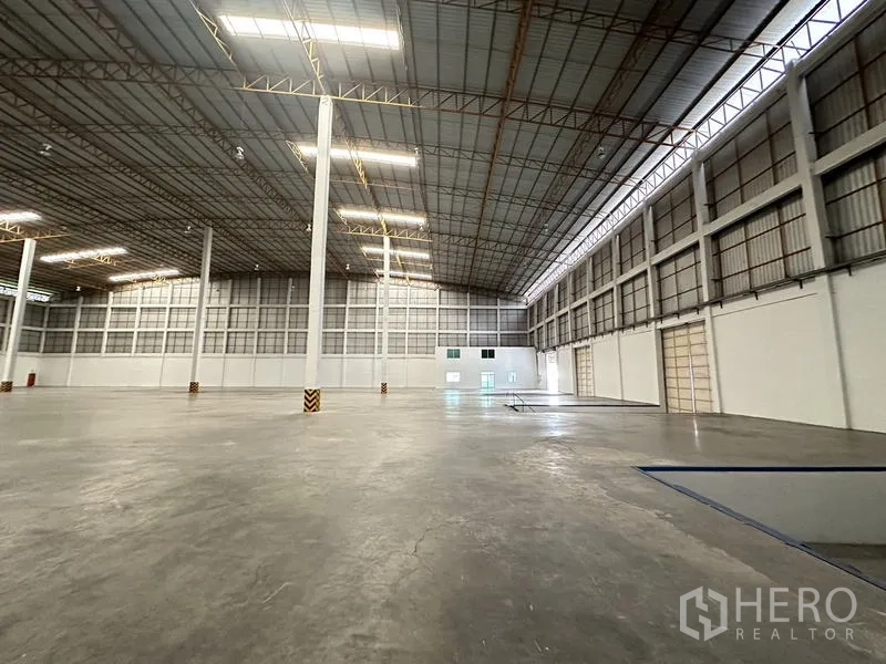 货栈 出租在Phra Nakhon Si Ayutthaya - 室内角度，展示天窗带、墙面板与多樘卷门。