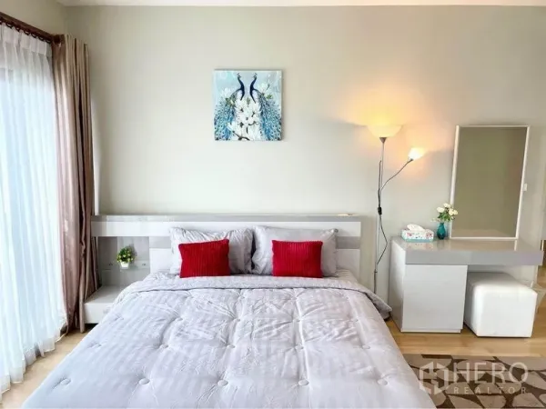 คอนโด ให้เช่าในWatthana, Bangkok - ห้องนอนมาสเตอร์สว่าง โปร่ง เตียงคิง งานศิลป์นกยูง โต๊ะเครื่องแป้ง และโคมไฟ ข้างม่านสูงจรดเพดาน