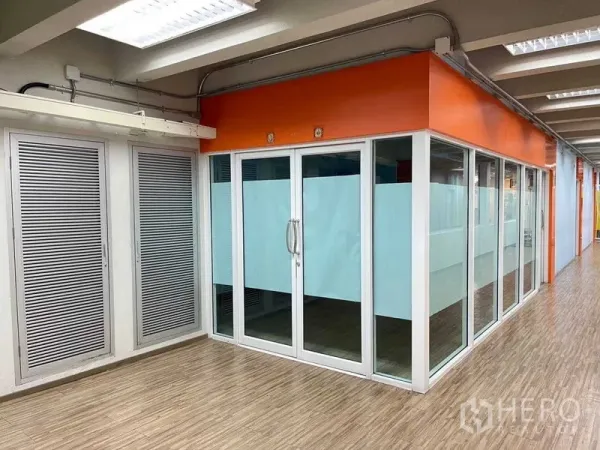 สำนักงาน ให้เช่าในRatchathewi, Bangkok - มุมสำนักงานกั้นกระจก โทนส้ม แถบฝ้ากระจก พื้นลายไม้ และไฟหลอดยาวสว่าง