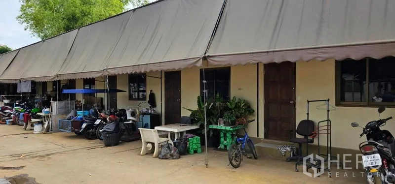 Warehouse for rent in Bang Kruai, Nonthaburi - Row of staff quarters under a long awning with motorbikes and plants outside.