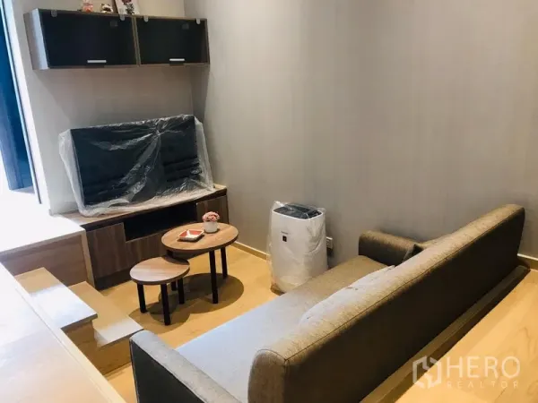 Condominium for rent or sale in Watthana, Bangkok - Sunken living room with sofa, nesting coffee tables and TV console under wall cabinets.