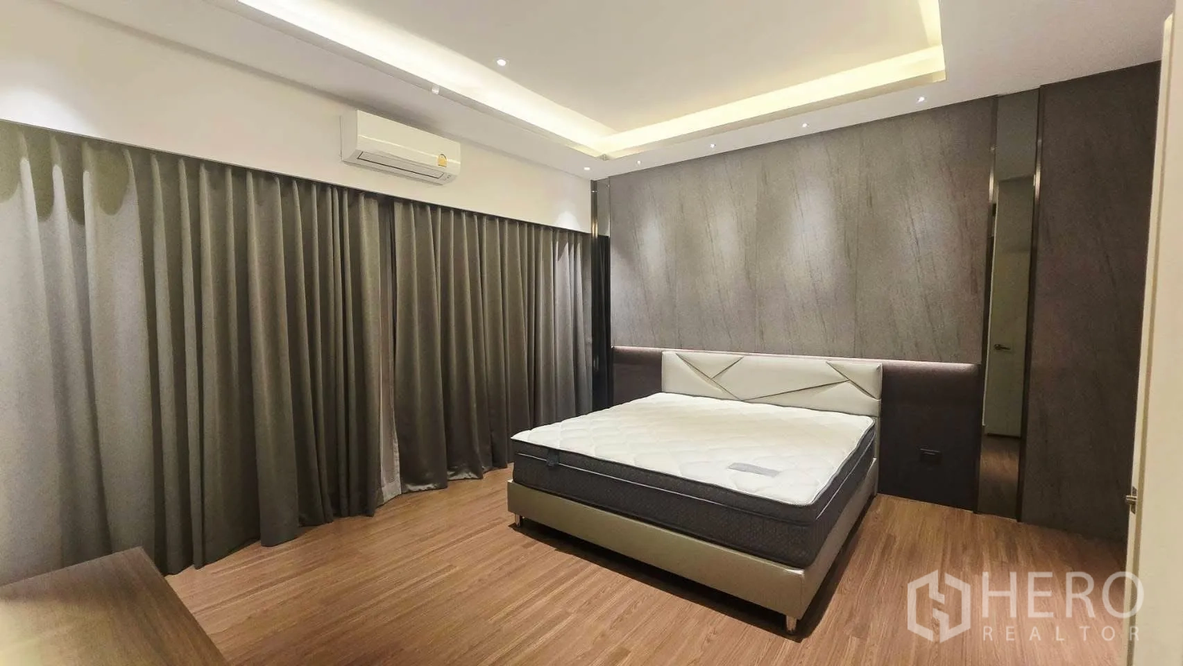 Detached House for rent in Prawet, Bangkok - Bedroom with feature wall, cove lighting, large bed and long curtains.