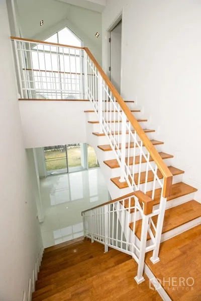 บ้าน ให้เช่าหรือขายในLam Luk Ka, Pathum Thani - บันไดไม้พร้อมราวเหล็กสีขาวเชื่อมต่อสู่ชั้นล่าง