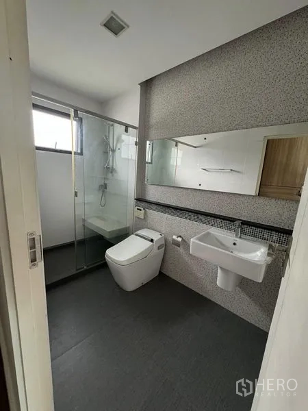 Detached House for rent in Samut Prakan - Bright bathroom with glass-enclosed shower, wall-mounted sink and toilet.