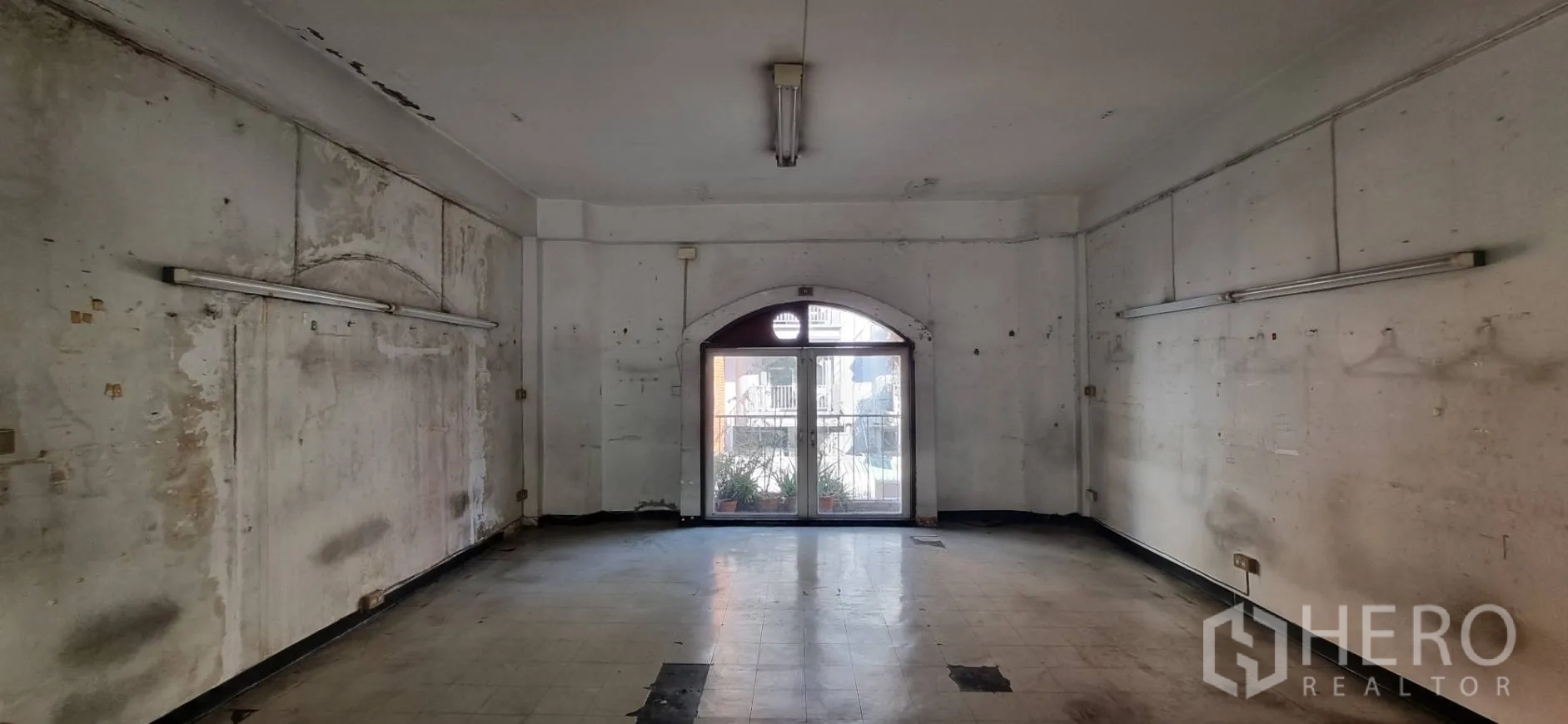 店屋 出租或出售在Bangkok - 宽阔房间，通过拱形玻璃门可见阳台花盆。