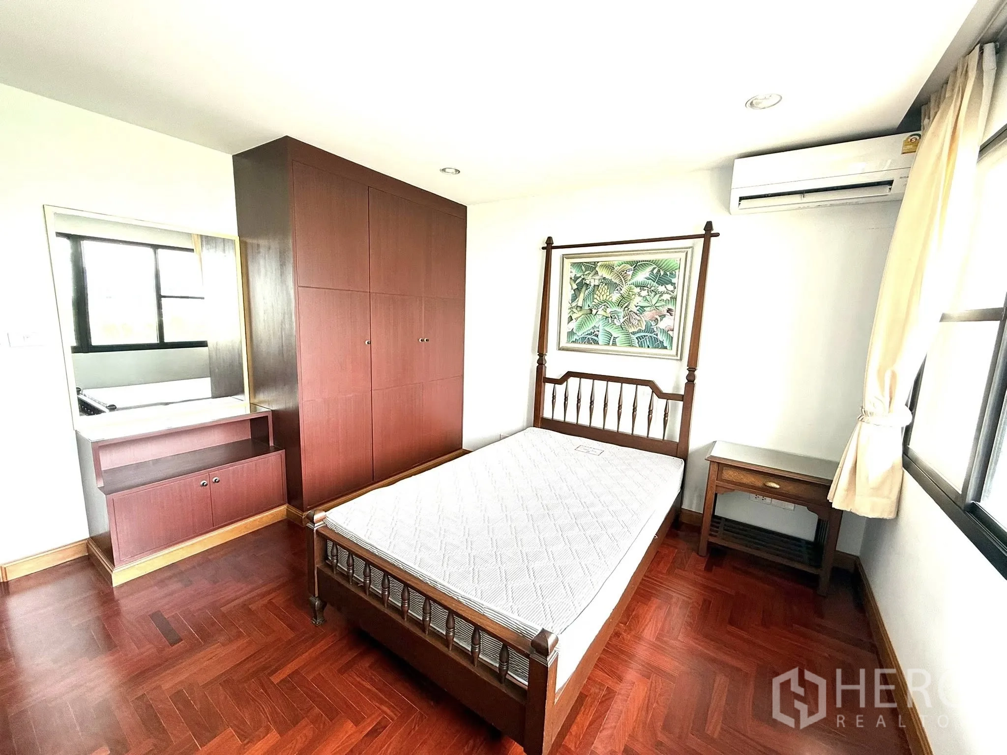 Condominium for rent in Sathon, Bangkok - Second bedroom with wooden bed, wardrobe and dressing nook.