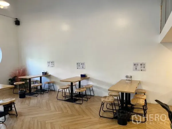 อาคารพาณิชย์ ให้เช่าในPhra Khanong, Bangkok - มุมที่นั่งสไตล์มินิมอล ผนังสีขาว โต๊ะไม้และสตูลบนพื้นลายก้างปลา.