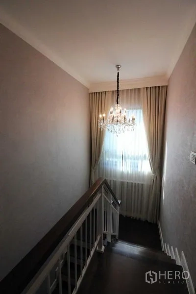 独立式住宅 出租在Prawet, Bangkok - 楼梯平台配水晶吊灯与落地窗帘。