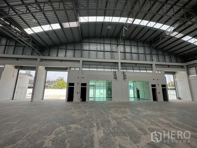Factory for rent in Khlong Luang, Pathum Thani - Warehouse wall with large openings and internal office blocks behind glass panels.